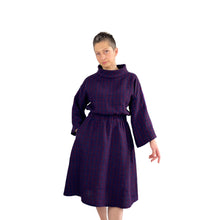 Load image into Gallery viewer, Edith sewing pattern – mid-length linen dress with elasticated waist, long wide sleeves, and funnel neck, front view in plum and navy checkered fabric, model with right hand in pocket