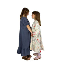 Load image into Gallery viewer, two finished May dresses on models facing each other and holding hands, both long with bottom frill, one with short puff sleeves and the other with long bishop sleeves