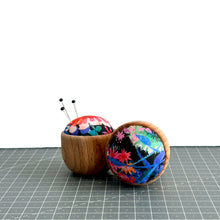 Load image into Gallery viewer, a handmade pincushion in liberty fabric on a wooden base, three pins on it, and one pincushion on its side to show the cute floral fabric, tresco