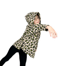 Load image into Gallery viewer, Side view of child model wearing Wren Pullover View A hoodie in leopard print fabric, hood up, balancing on one leg with right arm lifted.