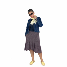Load image into Gallery viewer, Olive skirt sewing pattern, View D — front view of mid-length tiered skirt with ruffle and curved high-low hem, integrated front pocket, made in polka dot fabric, worn with a denim jacket and yellow scarf