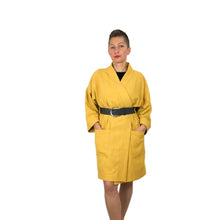 Load image into Gallery viewer, The Overlap sewing pattern by dhurata davies, front view of the yellow long version, worn with a leather belt, with both hands inside the front patch pockets