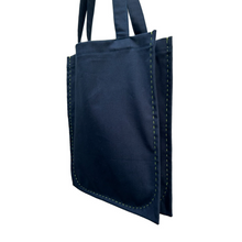 Load image into Gallery viewer, twin tote, bag sewing pattern by dhurata davies, hanging from both handles, showing the side view of the bag compartments. made in a navy blue fabric with lime green stitching