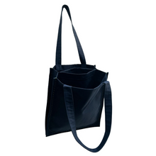 Load image into Gallery viewer, twin tote, bag sewing pattern by dhurata davies, hanging from one handle, showing the inside structure of the bag compartments. made in a navy blue fabric with lime green stitching