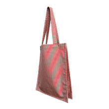 Load image into Gallery viewer, twin tote, bag sewing pattern by dhurata davies, hanging from both handles, showing the side view of the bag compartments. made in a striped red and tan fabric