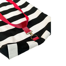 Load image into Gallery viewer, A close-up of a black and white striped fabric tote bag with bright red handles and a gold-tone metal ring clasp, shown on a plain white background.