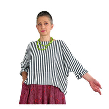 Load image into Gallery viewer, Woman wearing the Rea Top sewing pattern in blue and white striped fabric, hand extended to show pleated cuff, styled with a red skirt
