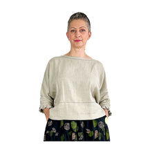 Load image into Gallery viewer, Woman wearing the Rea Top sewing pattern in natural linen with pleated cuffs, styled with black patterned skirt, hands in pockets
