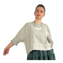 Load image into Gallery viewer, Woman wearing the Rea Top sewing pattern in natural linen, hand extended to show the sleeve shape
