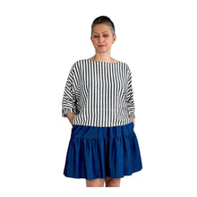 Load image into Gallery viewer, Woman wearing the Rea Top sewing pattern in blue and white stripes, styled with a blue mini skirt, hands in pockets