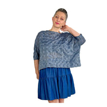Load image into Gallery viewer, Woman wearing the Rea Top sewing pattern in blue textured fabric, styled with a blue mini skirt