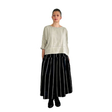 Load image into Gallery viewer, Woman wearing the Tia Skirt sewing pattern in midi length in black fabric with beige stripes, styled with a beige top