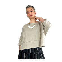 Load image into Gallery viewer, Woman wearing the Rea Top sewing pattern in natural linen, hand raised to neck to show the pleated cuff detail
