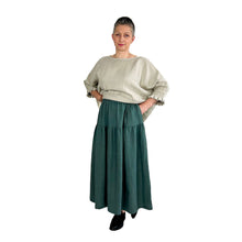 Load image into Gallery viewer, Woman wearing the Tia Skirt sewing pattern in teal, hand in pocket, styled with a beige top