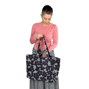 kulmi bag, sewing pattern by dhurata davies, bag held in right hand, left hand reaching inside the bag, made in light grey canvas fabric with large dark flowers 