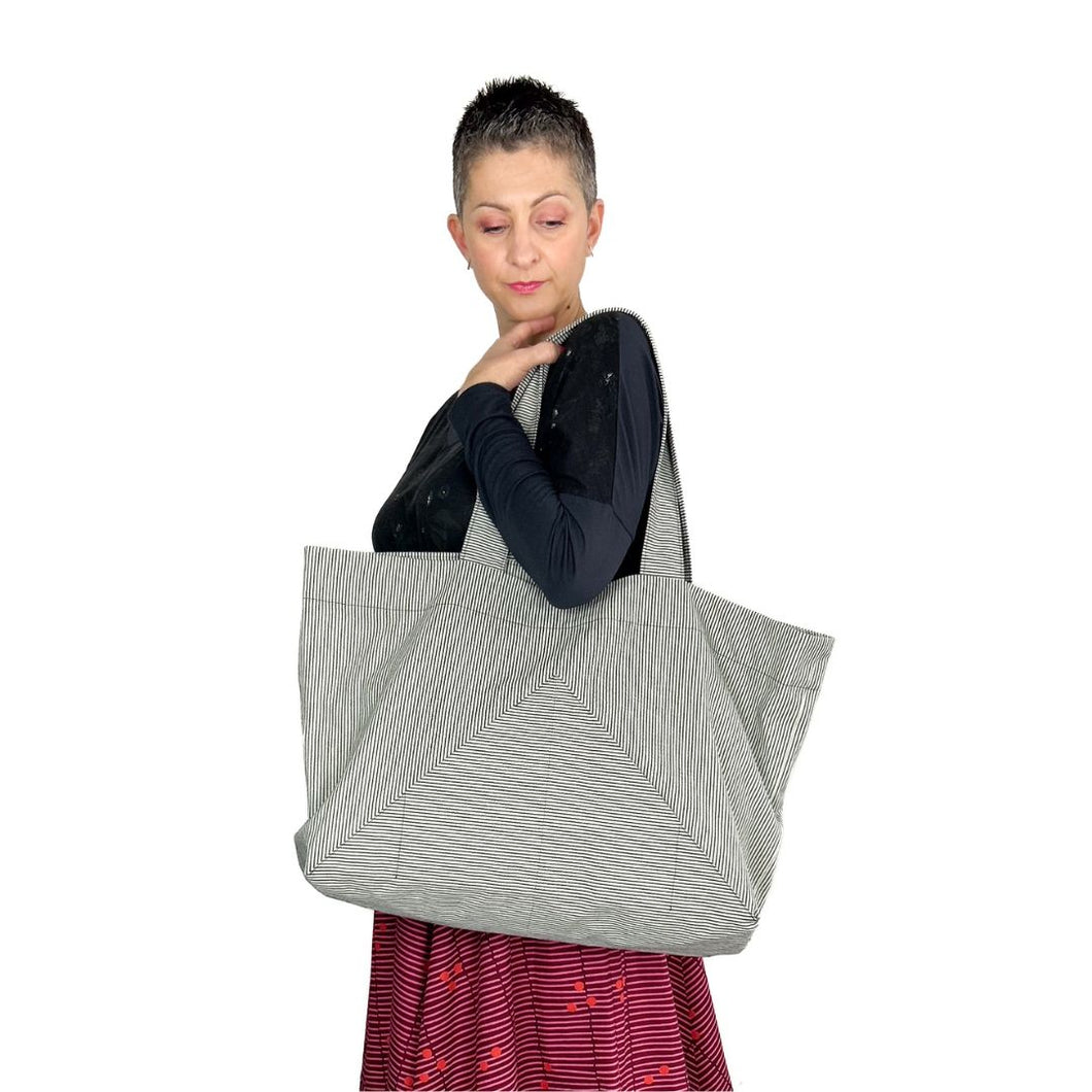 kulmi bag, sewing pattern by dhurata davies, bag worn in left arm, made in light grey canvas fabric with thin dark stripes, highlighting the pocket shape